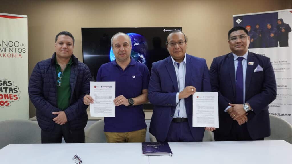 Cuatro hombres, representantes de Emergent Cold LatAm y del banco de alimentos Diakonía sonríen mirando a la cámara. Los dos hombres en el centro sostienen en sus manos las copias del acuerdo firmado entre las instituciones.