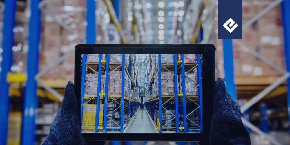 en primer plan estan manos agarrando una tablet y al fondo un almacen